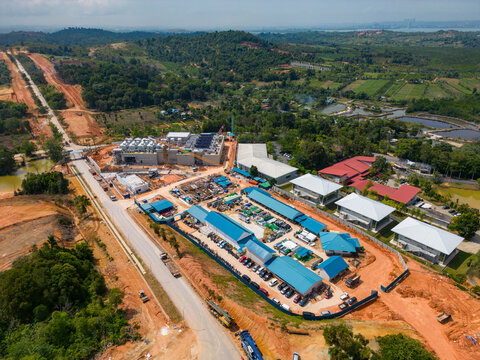 Aerial view of Data Center Nongsa construction site with surrounding red earth, lush greenery, and access roads in Batam, Riau Islands, Indonesia.