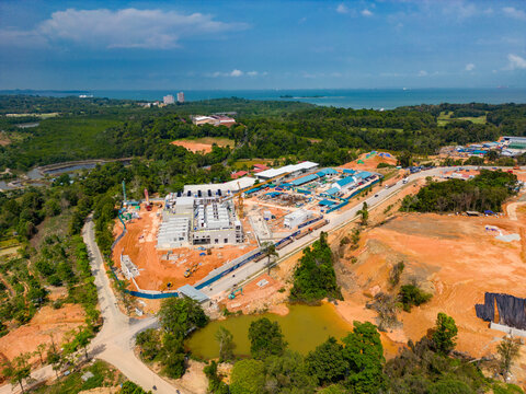 Aerial view of the Data Center Nongsa construction site featuring modern industrial buildings, heavy machinery, and surrounding lush greenery in Batam, Riau Islands, Indonesia.