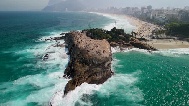 Aerial view of Arpoador Rock with crashing waves and the coastline of Rio de Janeiro, Rio de Janeiro, Brazil.