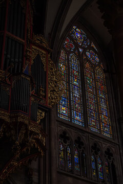 Historic gothic church interior detail featuring a majestic pipe organ and colorful stained glass windows.