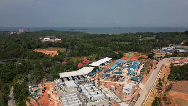 Aerial view of Hyperlapse the Data Center in Nongsa construction site featuring industrial buildings, red earth, and surrounding greenery in Batam, Riau Islands, Indonesia.