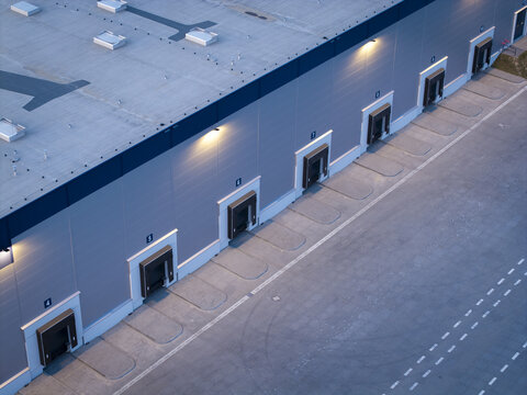 Aerial view of a modern logistics hub featuring multiple numbered loading docks and a large paved yard at dusk in Krakow, Lesser Poland Voivode, Poland.