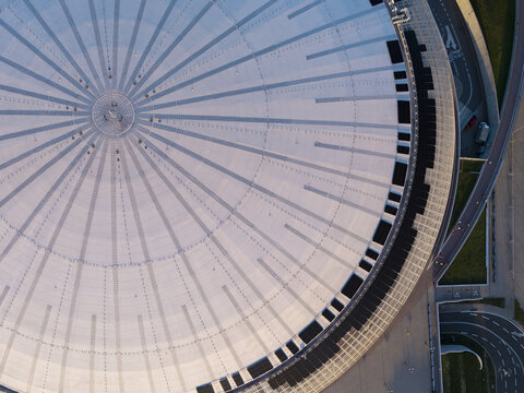 Aerial view of the circular roof of Tauron Arena Krakow with its distinctive radial structure and solar panels, surrounded by paved areas and roads in Krakow, Lesser Poland Voivode, Poland.