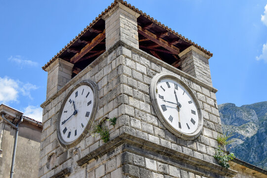 View of the historic stone clock tower in the old town with weathered masonry and blue sky background in Kotor, Kotor Municipality, Montenegro.
