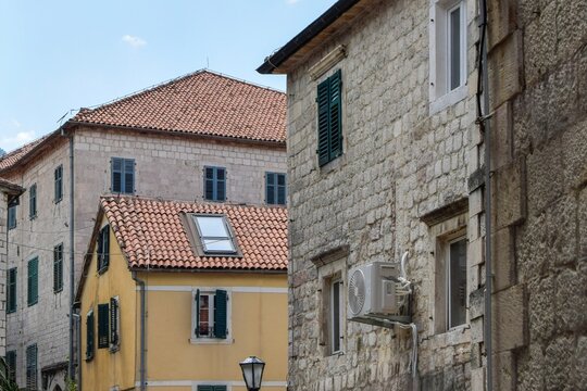 View of historic stone buildings with terracotta roofs and green shutters in the Old Town of Kotor, Kotor Municipality, Montenegro.