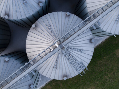 Aerial view of metal grain silos with industrial catwalks and circular roofs in Lesser Poland Voivode, Poland.