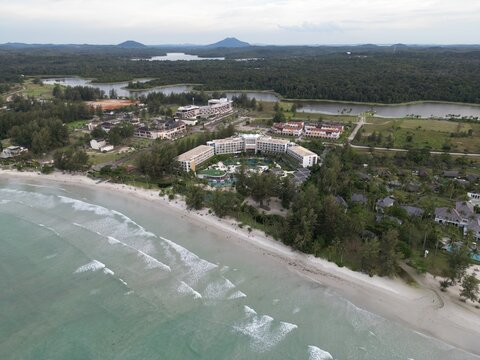 Aerial view of Lagoi Bay Resort Bintan featuring modern hotel architecture nestled along a sandy beach with turquoise waters and lush tropical greenery in Bintan, Kepulauan Riau, Indonesia.