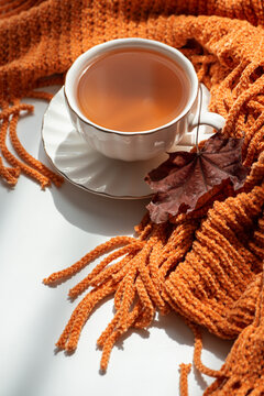 Cozy warm beverage with textured scarf and autumn leaf, perfect for fall season relaxation and comfort