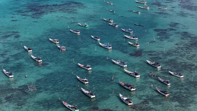 Aerial view of traditional wooden fishing boats anchored in the clear turquoise waters of the Karimunjawa archipelago in Karimunjawa, Central Java, Indonesia.