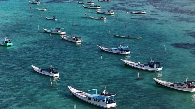 Aerial view of traditional wooden fishing boats floating in the clear turquoise water of the sea in Karimunjawa, Central Java, Indonesia.