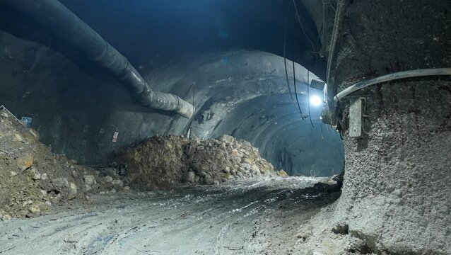 View of an underground tunnel construction site with rough rock walls, a large pile of excavated earth, and industrial lighting in Istanbul, Istanbul, Turkiye.