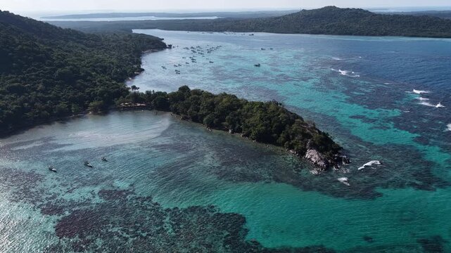 Aerial view of a tropical island surrounded by vibrant coral reefs and crystal clear turquoise water in Karimunjawa, Central Java, Indonesia.