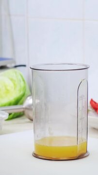 Chef in professional white kitchen make sweet sause with honey and orange juice in blender cup. Cooking, preparing ingredients in restaurant interior. Healthy and diet food delivery concept. 4K shot