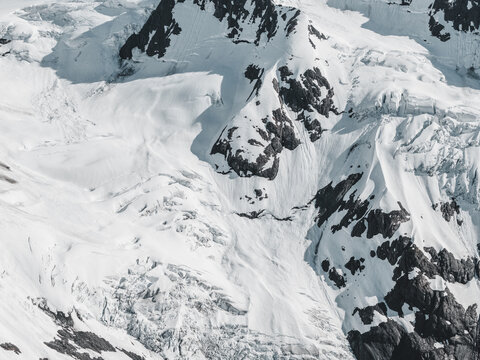 Aerial view of Byron Glacier featuring rugged ice formations, deep crevasses, and snow-covered mountain slopes in Anchorage, Alaska, United States.