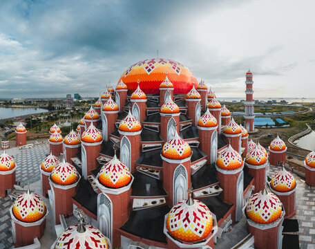 Aerial view of Masjid Kubah 99 Asmaul Husna with its distinctive colorful domes and minaret under a cloudy sky in Kecamatan Mariso, Sulawesi Selatan, Indonesia.