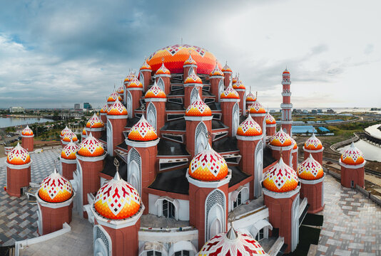 Aerial view of Masjid Kubah 99 Asmaul Husna with its distinctive colorful domes and intricate architectural design under a cloudy sky in Kecamatan Mariso, Sulawesi Selatan, Indonesia.