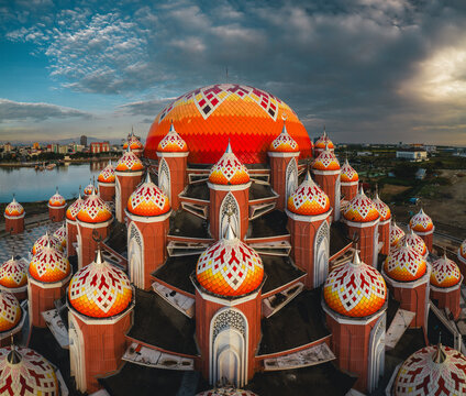 Aerial view of Masjid Kubah 99 Asmaul Husna with its distinctive colorful domes and intricate architectural details situated by the waterfront in Kecamatan Mariso, Sulawesi Selatan, Indonesia.
