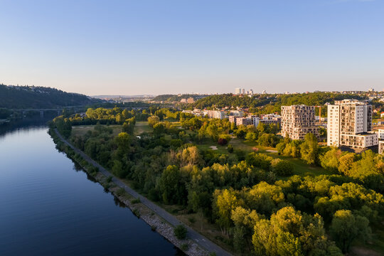 Aerial view of real modern buildings surrounded by city and nature. Residential place in the suburban area close to the river.