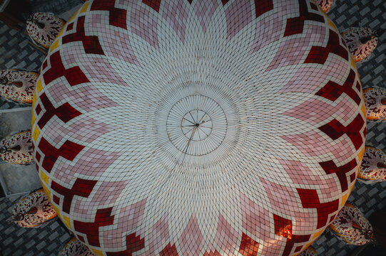 Aerial view of the intricate geometric dome of Masjid Kubah 99 Asmaul Husna featuring white, pink, and red patterns in Makassar, Sulawesi Selatan, Indonesia.