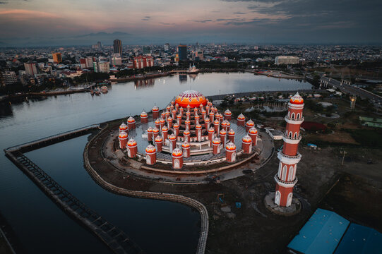Aerial view of the iconic Masjid Kubah 99 Asmaul Husna with its distinctive colorful domes and tall minaret, situated on the waterfront in Kecamatan Mariso, Sulawesi Selatan, Indonesia.