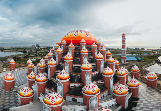 Aerial view of Masjid Kubah 99 Asmaul Husna with its distinctive colorful domes and intricate architectural patterns by the waterfront in Kecamatan Mariso, Sulawesi Selatan, Indonesia.