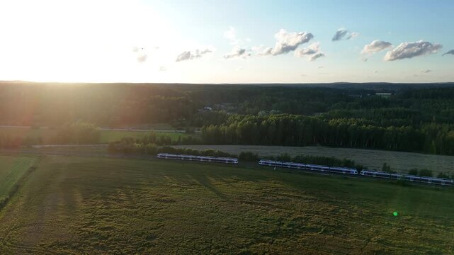 Drone footage of two trains traveling in opposite directions and passing each other on parallel tracks during golden sunset light in a scenic natural landscape