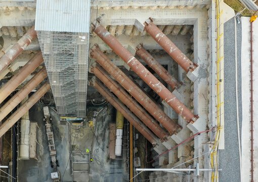 Aerial view of a deep construction excavation site featuring large steel support struts, concrete retaining walls, and heavy machinery in Istanbul, Istanbul, Turkiye.