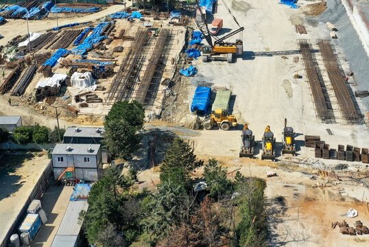 Aerial view of a construction site featuring heavy machinery, cranes, and stacks of rebar with temporary site offices in Istanbul, Istanbul, Turkiye.