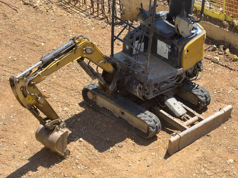 View of a yellow mini excavator parked on a dirt construction site in Istanbul, Istanbul, Turkiye.
