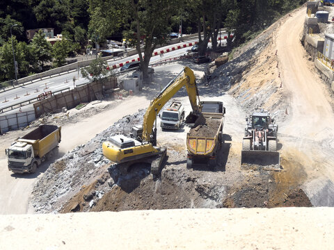 View of heavy construction machinery including an excavator and dump trucks working on a road expansion project in Istanbul, Istanbul, Turkiye.