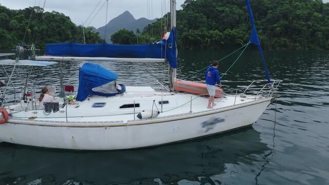 Sailing family. Sailing boat anchored in the tropical bay with family on board