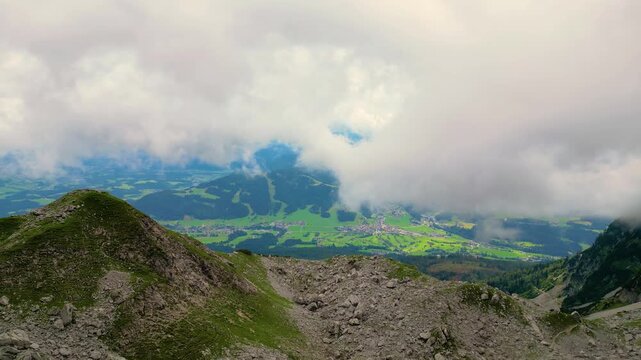 Aerial view of the village of Ellmau nestled in a green valley below the Wilder Kaiser mountains with rocky slopes and clouds in the sky, Ellmau, Tyrol, Austria.