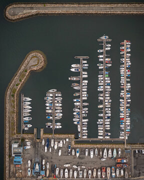 Aerial view of the marina in Vilanova de Arousa with sailboats and motorboats docked in rows along the piers, protected by a stone breakwater in Vilanova de Arousa, Pontevedra, Spain.