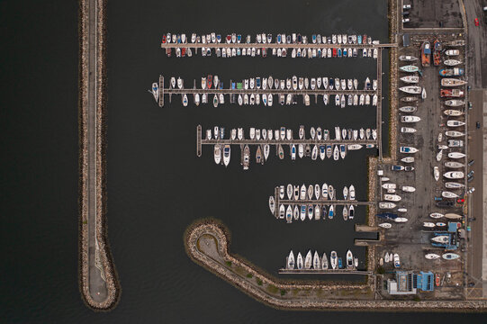 Aerial view of the marina with numerous boats docked in rows along the piers and breakwater in Vilanova de Arousa, Pontevedra, Spain.