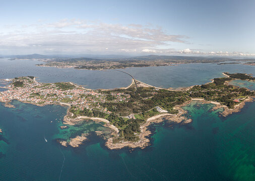 Aerial view of A Illa de Arousa island featuring its coastal town, sandy beaches, turquoise waters, and the connecting bridge in A Illa de Arousa, Pontevedra, Spain.