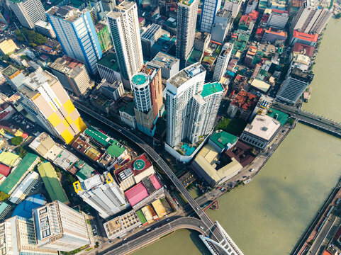 Aerial view of the dense urban skyline of Manila featuring modern skyscrapers, the winding Pasig River, and a bridge crossing the water in Manila, Metro Manila, Philippines.