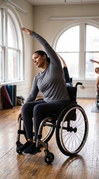 A focused woman sitting in a wheelchair stretches her arm overhead during a group fitness class. The bright studio creates an atmosphere of inclusion. Ideal for healthcare or fitness marketing.