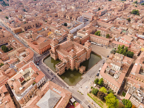 Aerial view of Estense Castle surrounded by its moat in the historic city center of Ferrara, with terracotta rooftops and urban streets. Ferrara, Emilia-Romagna, Italy.