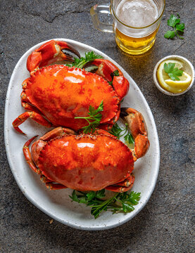 Whole cooked  crabs on white plate with lemon and beer. Top view