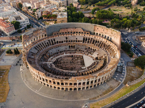 Aerial view of the historic Colosseum amphitheatre surrounded by urban streets and ancient ruins in the heart of the city of Roma, Lazio, Italy.
