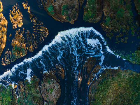 Aerial view of Venta Rapid, the widest waterfall in Europe, with its cascading water flowing over rocky formations and lush green banks in Kuldiga, Kuldiga Municipality, Latvia.