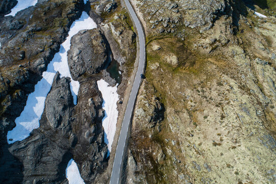 Aerial view of the winding Aurlandsfjellet road cutting through a rugged mountainous landscape with rocky terrain and patches of snow in Aurland, Vestland, Norway.