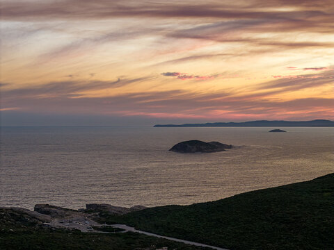 Aerial view of the rugged coastline and islands of Torndirrup National Park at sunset with soft clouds in the sky in Torndirrup, Western Australia, Australia.