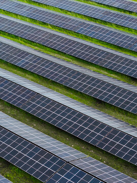 Aerial view of solar panels arranged in long rows across a green field in Suntazi, Ogre Municipality, Latvia.