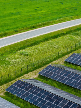 Aerial view of solar panels installed in a green field next to a road in Suntazi, Ogre Municipality, Latvia.