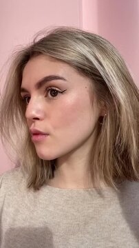 Young girl, woman doing everyday casual makeup, drawing black eyeliner, eyeshadow, applies dramatic winged eyeliner to eyes. Close up visage, cosmetic, mascara. Real life vertical ugc video. Beauty