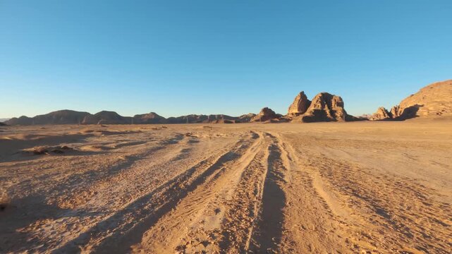 Driving in Wadi Rum at afternoon, car goes over sandy desert, sandstone sunlit mountains background distance, pov video