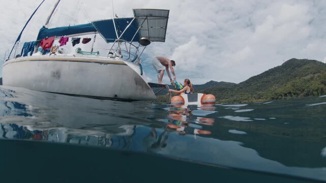 Splitted underwater view of the sailing boat with family with kids on it