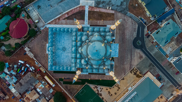Accra, Ghana - 12 October 2021: Aerial view of the Ghana National Mosque Complex with its distinctive blue domes, minarets, and surrounding paved courtyard in an urban setting.