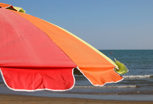 Bright colorful beach umbrella with ocean view on a sunny summer day